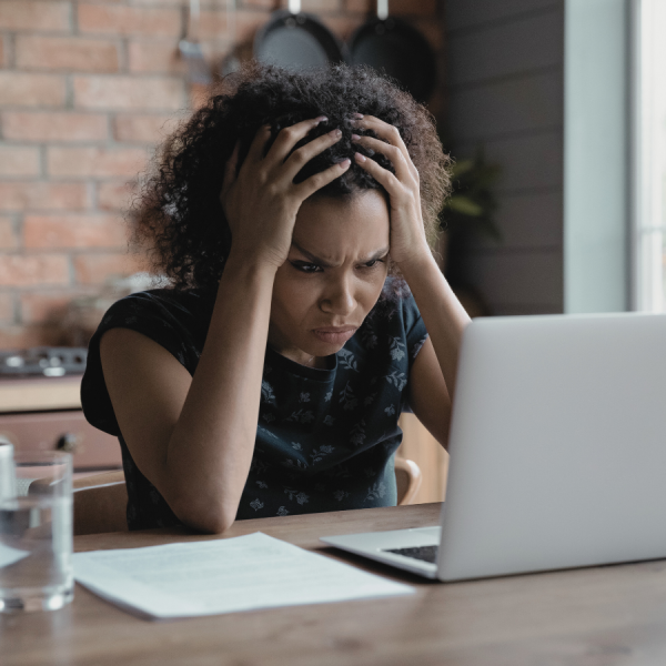 woman hands on head staring at computer